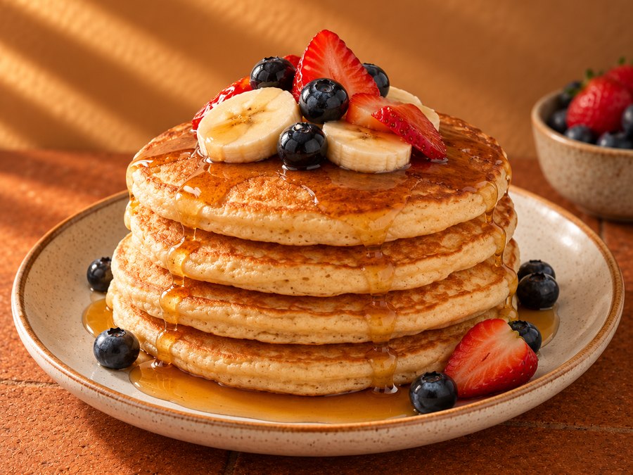 Stack of pancakes topped with berries and banana